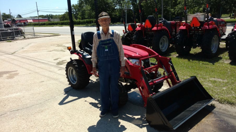 Mr. Doyt Spradley standing in front of his Mahindra Emax22 and loader